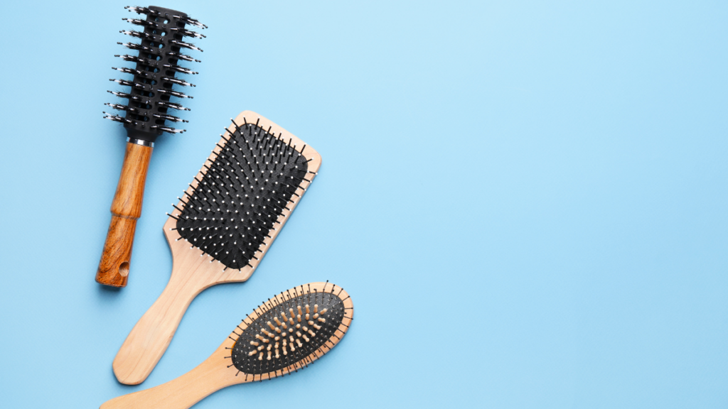 A set of wooden hairbrushes, including a paddle, round, and oval design, arranged neatly on a bright blue background.