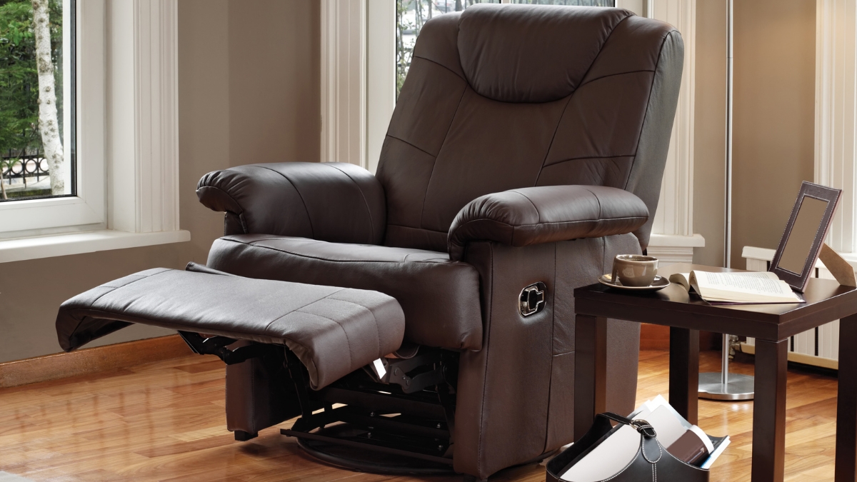 Brown leather swivel rocker recliner chair with extended footrest placed near a window in a cozy living room.