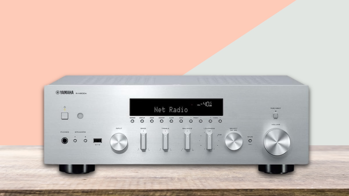 Silver Yamaha R-N600A receiver on a wood surface, showing front controls, display screen, and input options.
