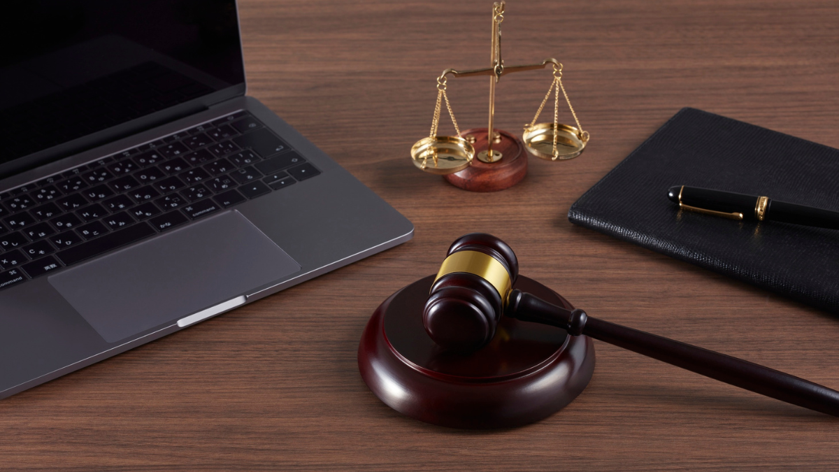 Legal gavel, scales of justice, laptop, and notebook on a desk representing family legal assistance and professional legal services.