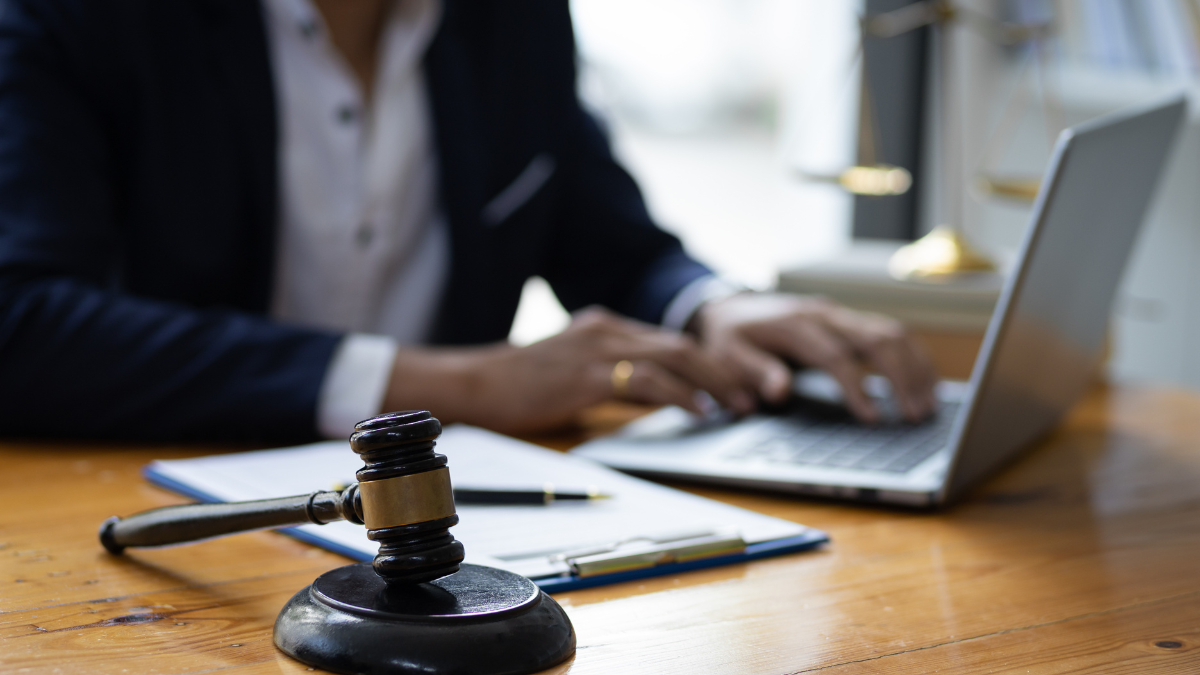 Legal advice services professional working on a laptop beside a judge’s gavel and legal documents.