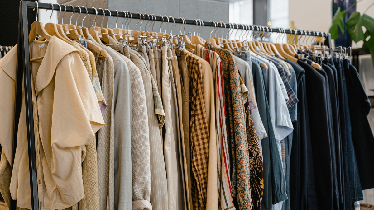 Kohl’s clothing display featuring shirts, pants, dresses, and casual apparel arranged on wooden hangers in a retail store.