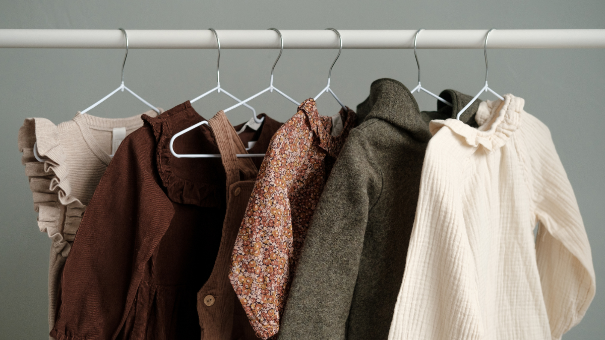 Affordable clothing in neutral earth tones hanging neatly on a white clothing rack.