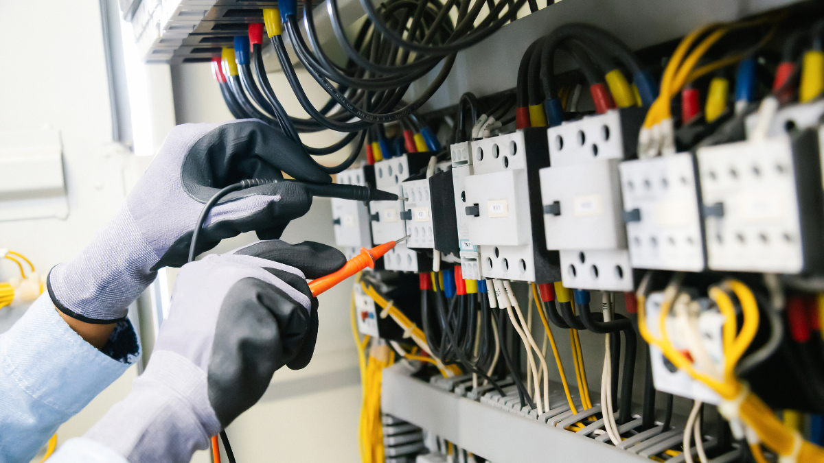 Electrician testing an electrical panel with voltage probes during professional electrical repair and maintenance.